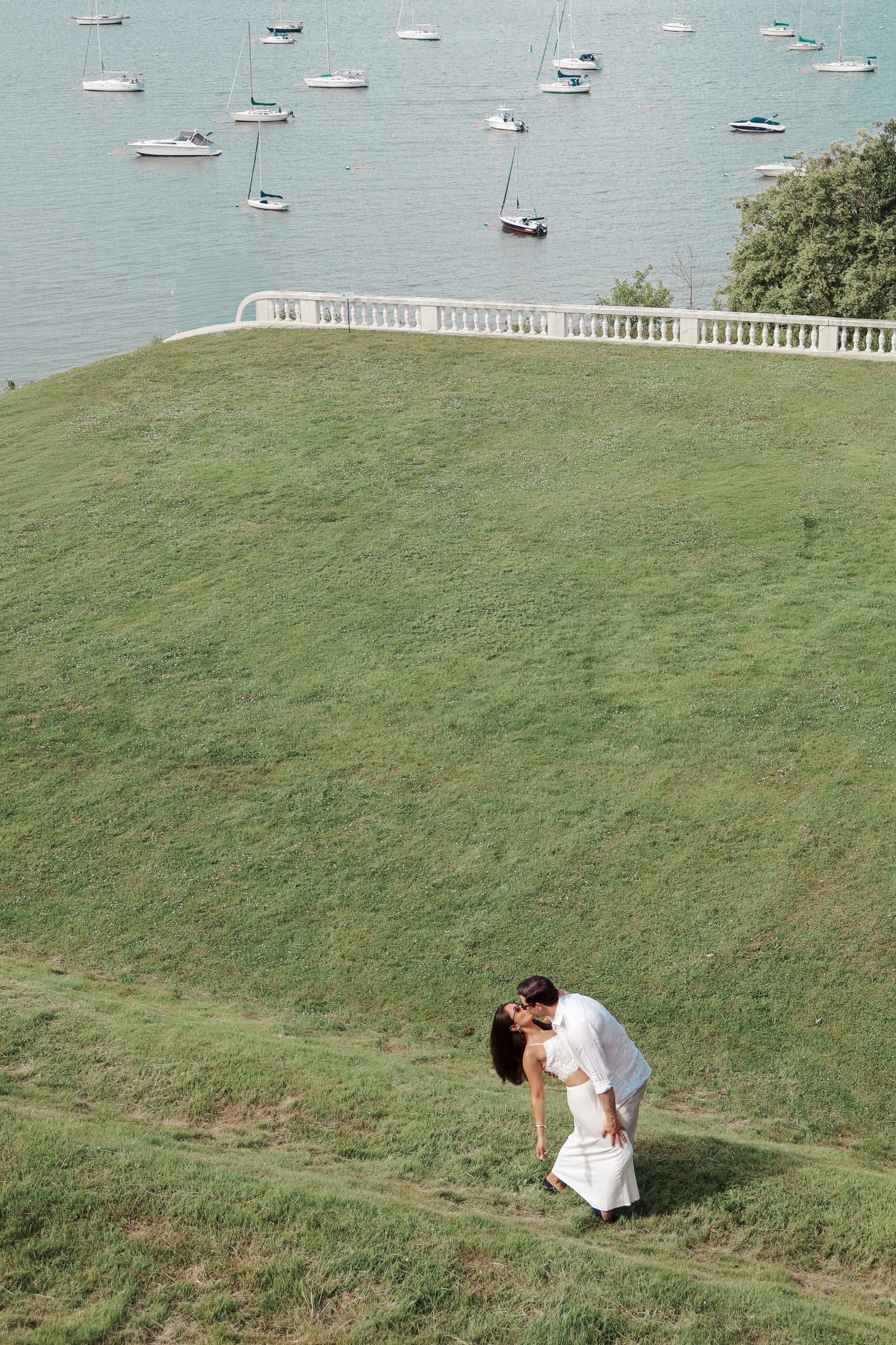 Couple kissing on lawn with sailboats
