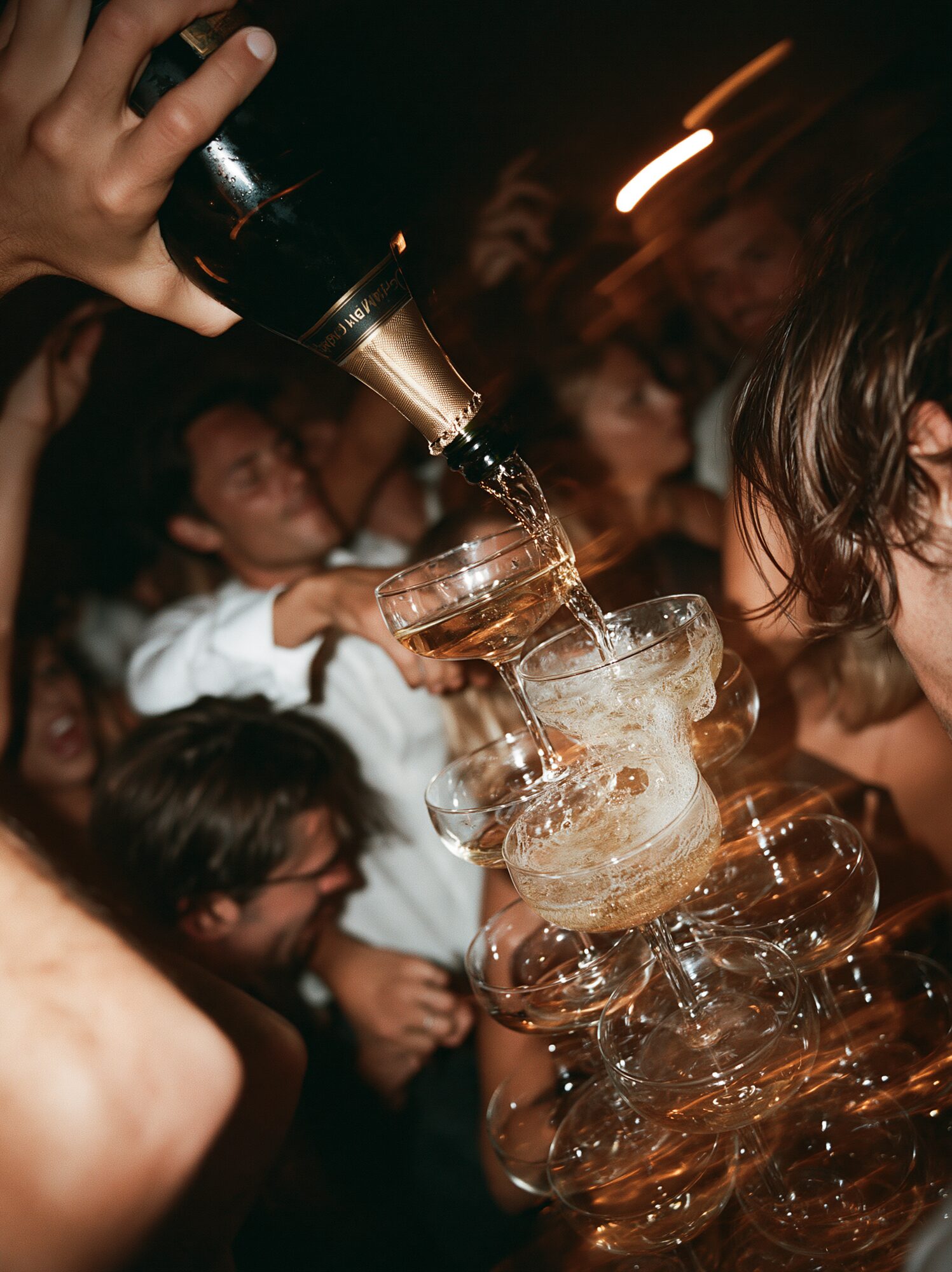 Champagne tower being poured at a wedding reception